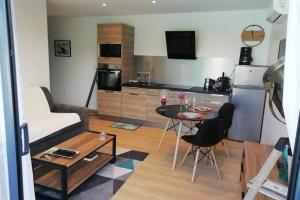 a living room with a small table and a kitchen at Entre Piscine et Mer in Tonnay-Charente