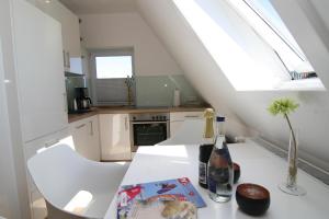 a kitchen with a white table with a bottle of wine at Am Wasser 4 OG in Hörnum