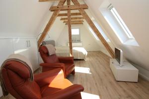 a attic room with a bed and two chairs and a television at Am Wasser 4 OG in Hörnum