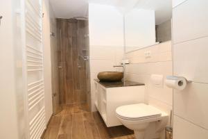 ein weißes Bad mit einem WC und einer Dusche in der Unterkunft Am Wasser 4 OG in Hörnum