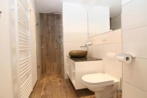 a white bathroom with a toilet and a shower at Am Wasser 4 OG in Hörnum