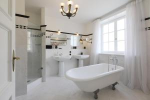 a white bathroom with a tub and a sink and a toilet at Ferienwohnung Art Deco in Hörnum +4 photos