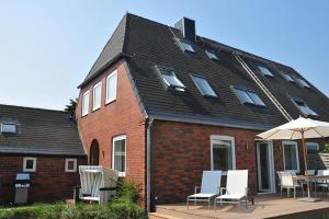 ein Haus mit einer Terrasse mit Stühlen und einem Sonnenschirm in der Unterkunft Budersandhaus in Hörnum