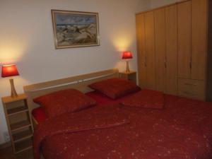 ヘルヌムにあるFerienwohnung Mertenの赤いベッド1台、赤い枕2つが備わるベッドルーム1室が備わります。