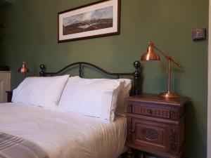 1 dormitorio con cama y mesita de noche con lámpara en Afallon Townhouse Gwynedd Room en Dolgellau