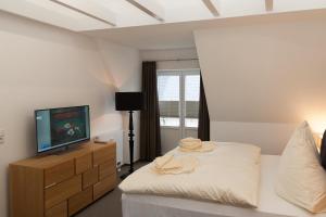 ヘルヌムにあるHaus Emilia - Appartement Leuchtturmのベッドルーム(ベッド1台、ドレッサー内のテレビ付)