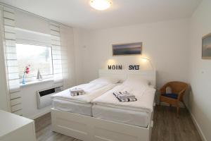 a white bedroom with a bed and a window at Haus Möwe, Luig in Hörnum