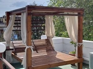 a wooden gazebo on a balcony with curtains at Mango Rooms in Rhodes Town