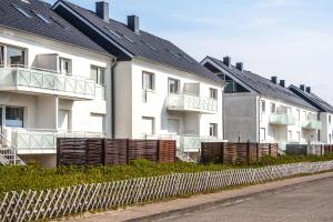a row of white houses with black roofs and a fence at Haus Möwe 5/22 in Hörnum