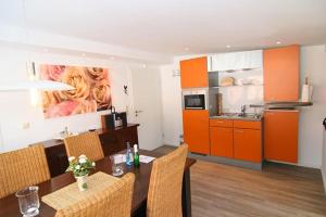 a kitchen with orange cabinets and a table with chairs at Haus Roseneck App.1 in Hörnum +1 photo