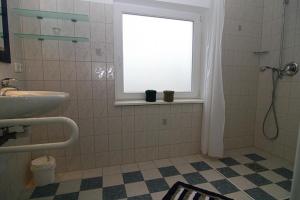 a bathroom with a shower and a sink and a window at Haus Roseneck App.1 in Hörnum