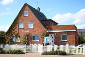 a red brick house with a white fence at Haus Roseneck App.1 in Hörnum