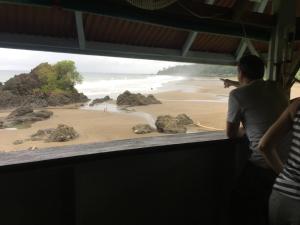 two people looking out at a beach from a window at The Hill B&B (El Morro Hosteria) in El Valle