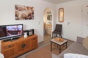 a living room with a television on a wooden entertainment center at Haus Roseneck App.2 in Hörnum