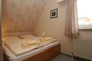 ein kleines Bett in einem Zimmer mit Fenster in der Unterkunft Haus Schumacher, Wohnung 1 in Hörnum