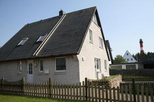 ein weißes Haus mit schwarzem Dach hinter einem Zaun in der Unterkunft Haus Schumacher, Wohnung 1 in Hörnum