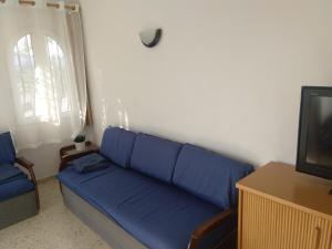 a living room with a blue couch and a tv at Apartamento Rey-Piscina in Denia