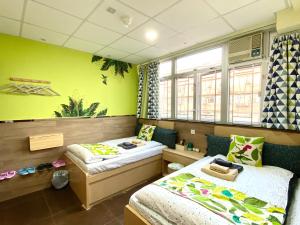 2 Betten in einem Zimmer mit grünen Wänden in der Unterkunft Paris Guesthouse-Tsim Sha Tsui Mansion in Hongkong