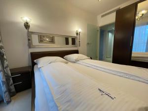 1 dormitorio con 2 camas con sábanas blancas y espejo en Wolin-Travel- Promenada Gwiazd 28 en Międzyzdroje