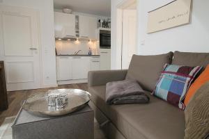 ein Wohnzimmer mit einem braunen Sofa und einem Tisch in der Unterkunft Lütje Deern in Hörnum
