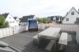 a deck with a bench and a table and chairs at Lütje Deern in Hörnum