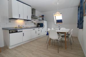 a kitchen with white cabinets and a table with chairs at Nils Holgerson 1 in Hörnum