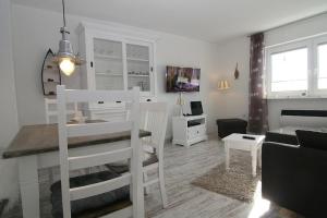 ein weißes Wohnzimmer mit einem Tisch und einem Sofa in der Unterkunft Lüddn Traum in Hörnum