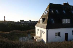 a white house with a black roof in a field at Pesel in Hörnum