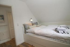 a white bed with pillows on it in a room at Strandperle 03 in Hörnum