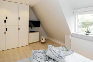 a bedroom with a bed with white cabinets and a window at Sylt Huus in Hörnum