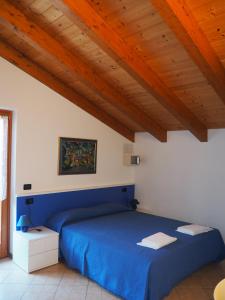 um quarto com uma cama azul e um tecto de madeira em Residenza Arcobaleno em Tenno