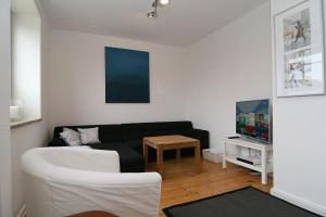 ein Wohnzimmer mit einem schwarzen Sofa und einem Tisch in der Unterkunft Ferienhaus TerpMeren in Hörnum
