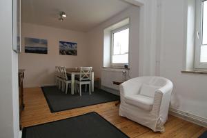 a living room with a white chair and a table at Ferienhaus TerpMeren in Hörnum