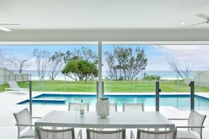 a dining room with a table and a swimming pool at Sentosa on Tugun - Beachfront 5 Bedroom in Gold Coast