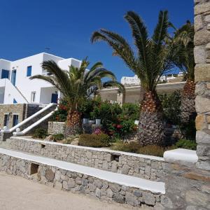 a stone retaining wall with palm trees in front of a building at Anixi Hotel in Ornos