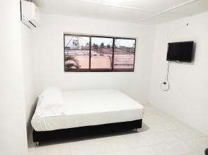 a white room with a bed and a window at Apartamentos Riohacha in Ríohacha