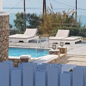 a swimming pool with two lounge chairs next to a swimming pool at Anixi Hotel in Ornos