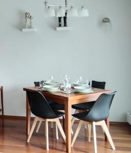 een houten tafel met stoelen, borden en glazen erop bij Antresola apartament Zeta Park in Ustroń