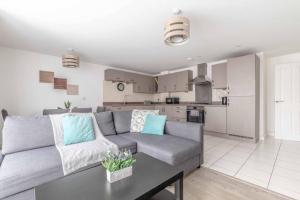 a living room with a gray couch and a kitchen at 2 BED & 2 BATH COSY APARTMENT SLOUGH- FREE PARKING in Slough