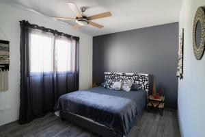 a bedroom with a bed and a ceiling fan at Rhum Cahuette T3 climatisé in Manapany-les Bains