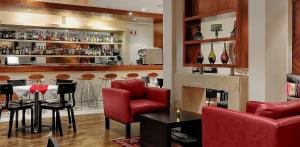 um restaurante com um bar com cadeiras vermelhas e um balcão em Ascot Hotel em Joanesburgo