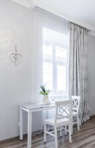 a white desk and two chairs in a room with a window at Golden Rose ! Apartments Lviv in Lviv