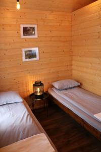 two beds in a log cabin with a side table at Cabanute Premium de pescuit in Sînmărghita