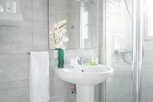 un bagno bianco con lavandino e specchio di Bubu Beach 4 a Los Cristianos Altre 27 foto