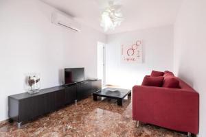 un soggiorno con un divano rosso e una TV di Bubu Beach 4 a Los Cristianos