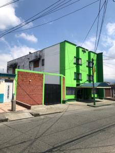 a green building on the side of a street at Hotel El Bosque in Armenia