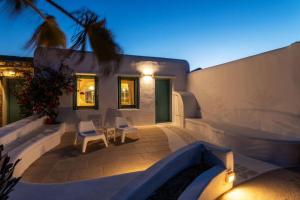 a backyard patio with white chairs and a house at Cycladic Luxury and Comfort in Kalo Livadi in Kalo Livadi