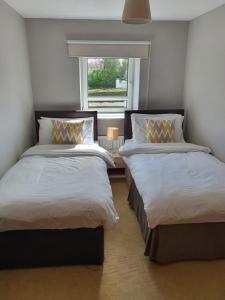 two beds in a room with a window at Kesh self catering holiday home. in Kesh