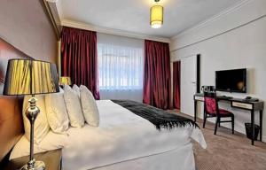Ascot Hotel في جوهانسبرغ: غرفة الفندق بسرير كبير ومكتب