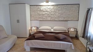 een slaapkamer met een groot bed en een bakstenen muur bij Apartments Janjac in Vodice